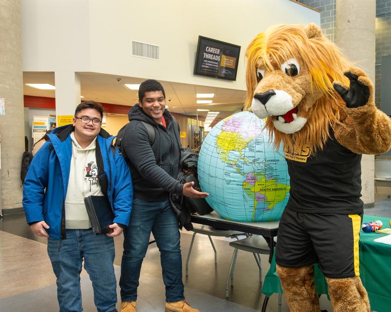 Roary with students holding a globe