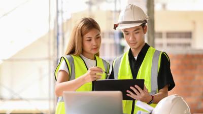 Two people in construction gear looking at notes