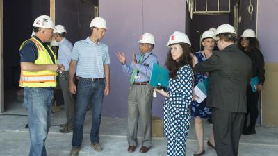 A group of inspectors in construction helmets tour a building under construction.