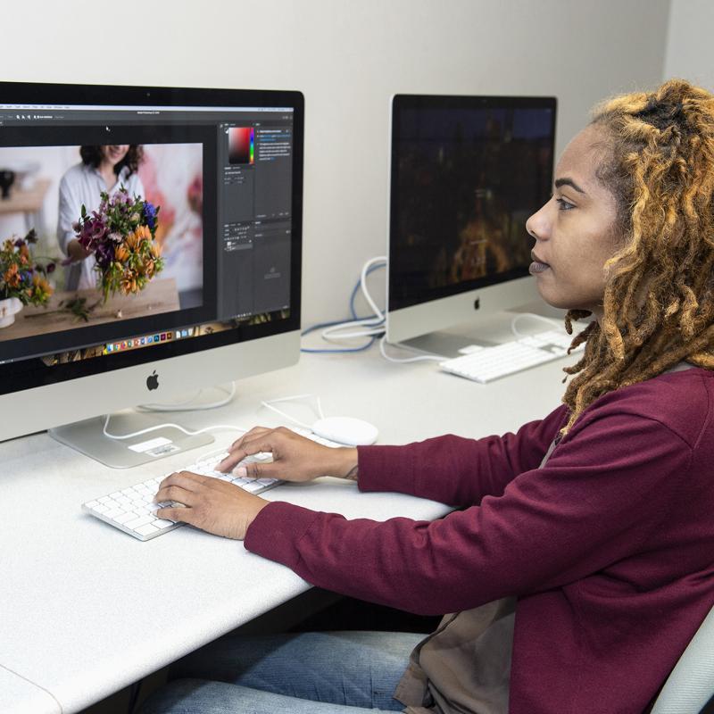 Woman works at computer on graphic design program.