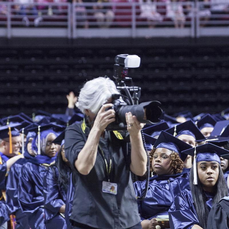 Photographer takes a picture at a graduation ceremony.