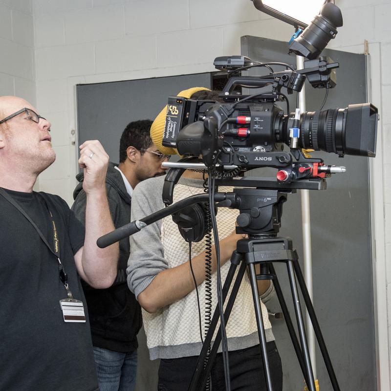 Cameraman looks through large video camera.