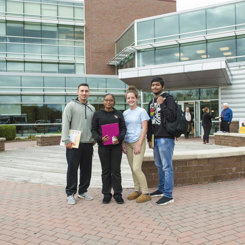 Four students pose at the entrance to the Northeast Regional Center.