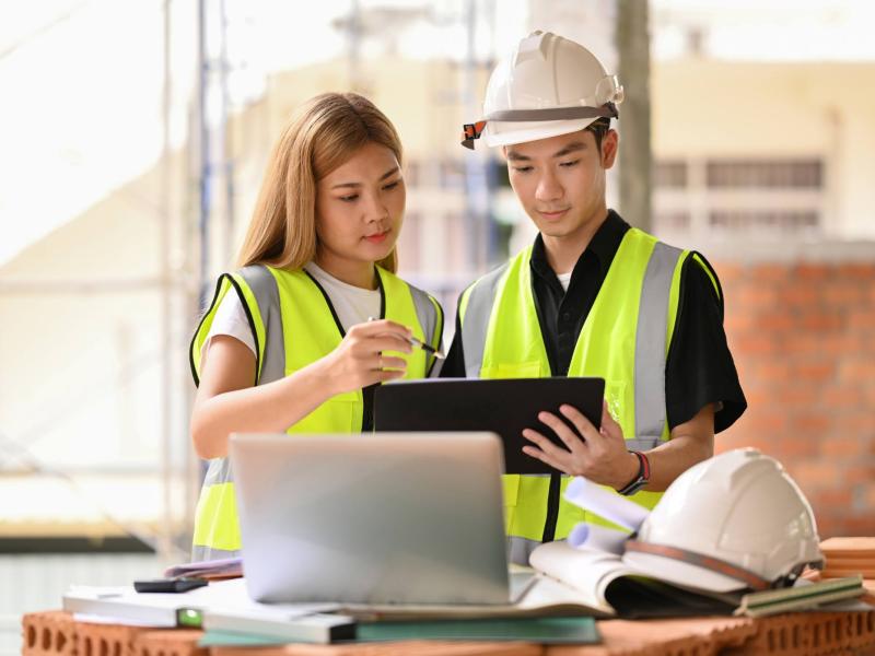 Two people in construction gear looking at notes