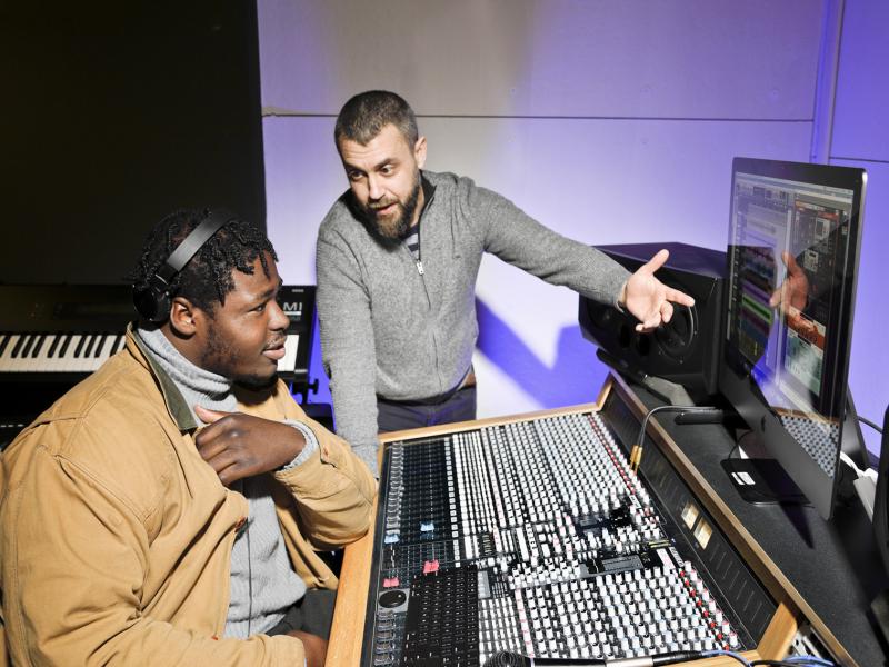 An instructor explains a soundboard to a student.