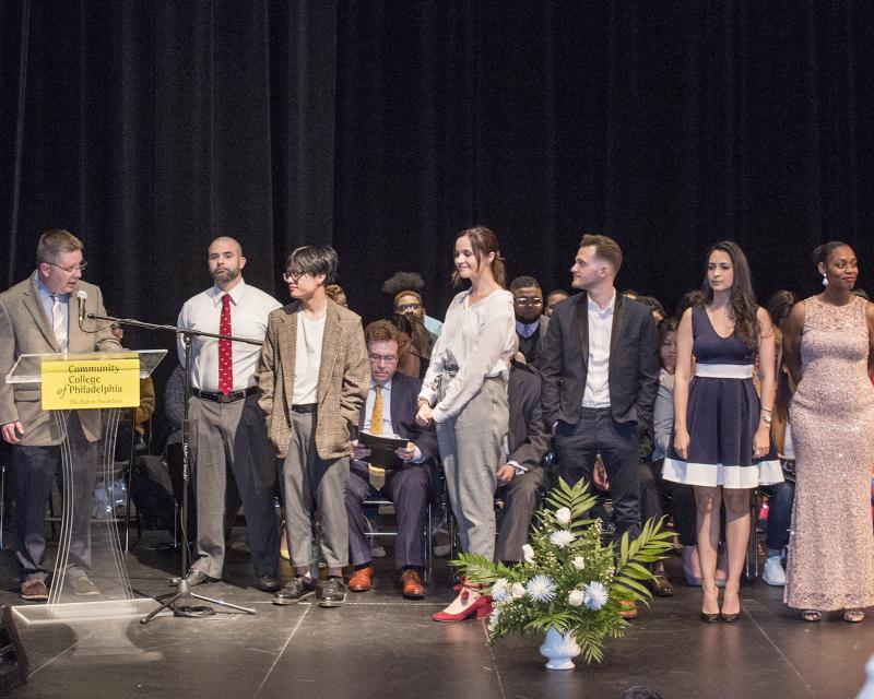 Students standing on a stage receiving academic awards