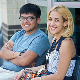 2 students sitting outside looking at camera