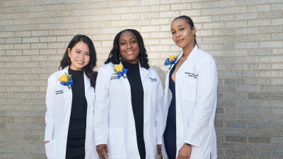 Public health students with lab coats smiling at the camers