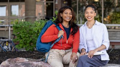 students smiling at the camera sitting on campus