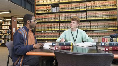 Two students student in a library of legal books.