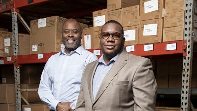 Two business owners in a warehouse pose for the camera.