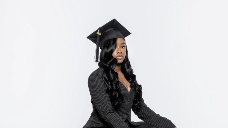 Ash jones's graduation photoshoot. She's wearing a black pinstripes pantsuit and a graduation cap. 