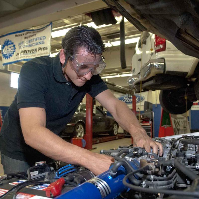 A mechanic works on an automotive engine.