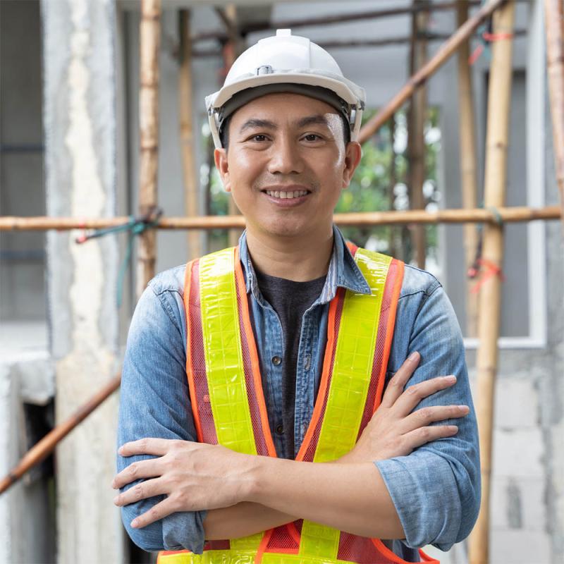 An engineer in construction safety gear smiles while on a job site