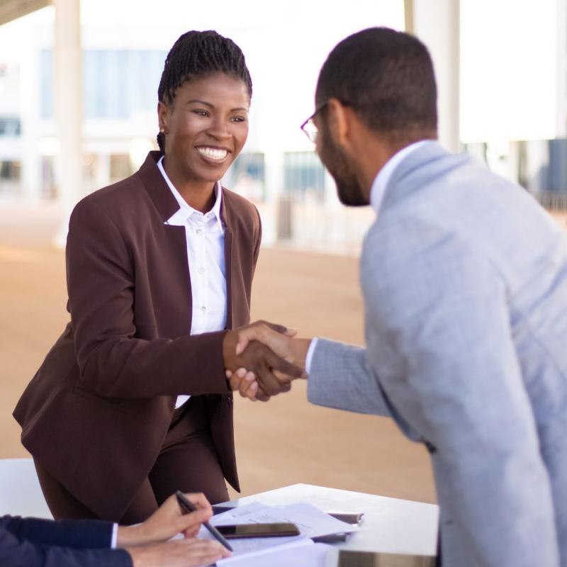 Woman in business attire shakes man's hand.
