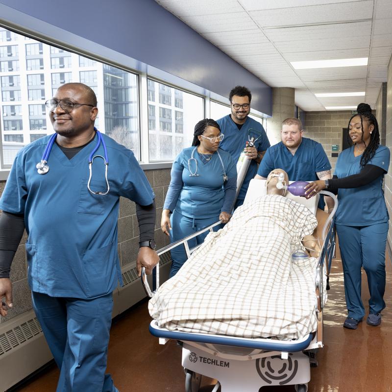 Students walking down the hall with a medical dummy 