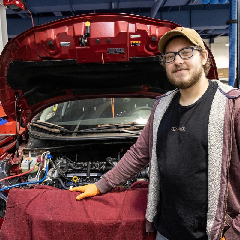 transportation technologies student standing at hood of car