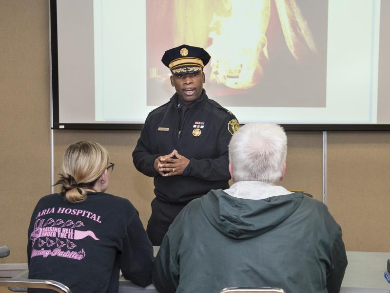 Instructor in firefighter uniform speaks to class.
