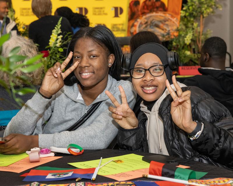 students at a black history month luncheon making a peace sign to the camera