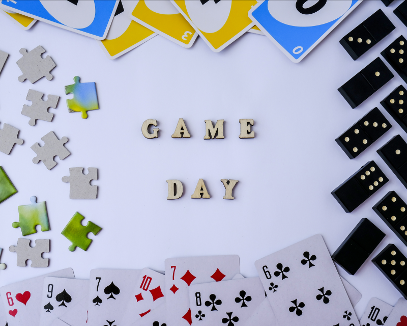 The word "game day" in block letters surrounded by dominos, playing cards, puzzle pieces and UNO cards