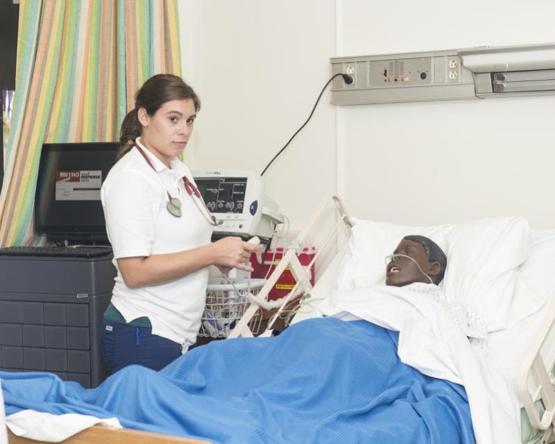 Nursing student standing over a mannequin "patient" 