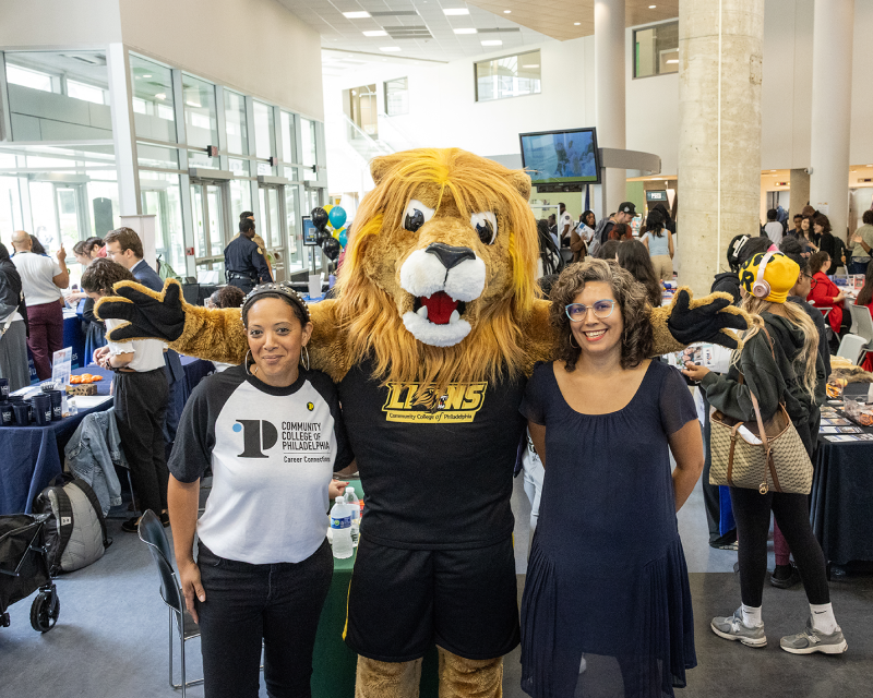 Roary standing with staff at a student event