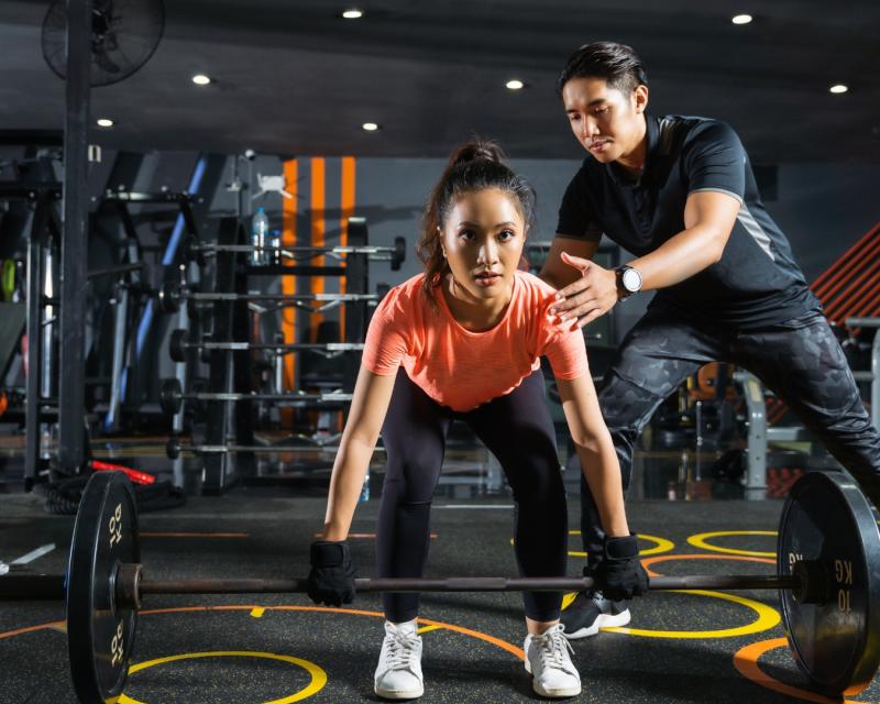 Fitness instructor working with a student on a dead lift. 
