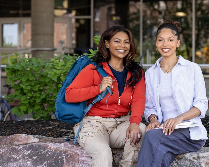students smiling at the camera sitting on campus