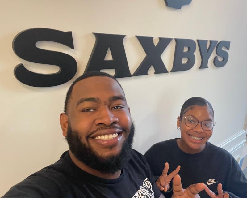 Workers in front of saxby sign