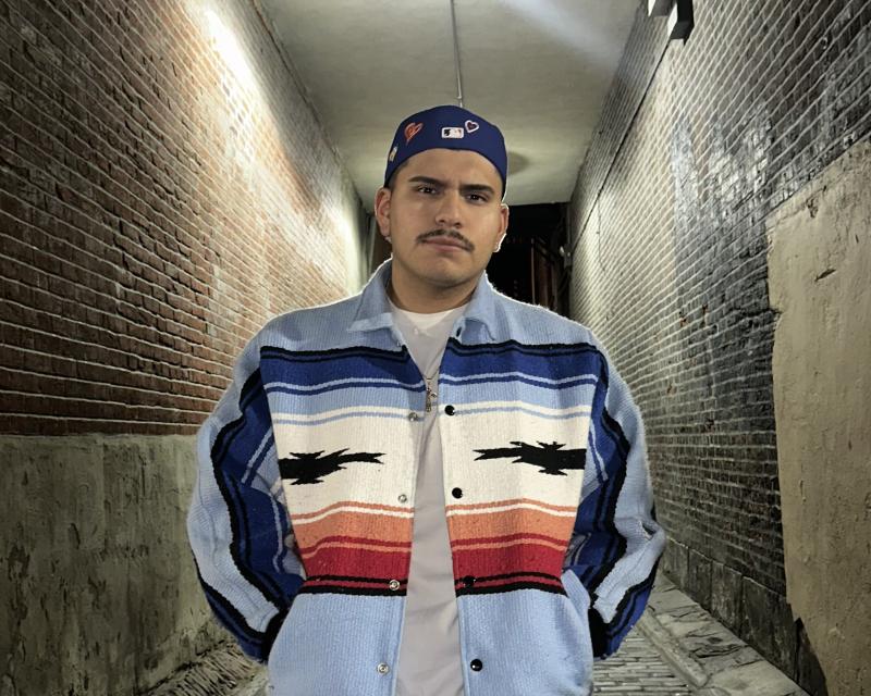 Brian Flores posing for photo in a brick hallway