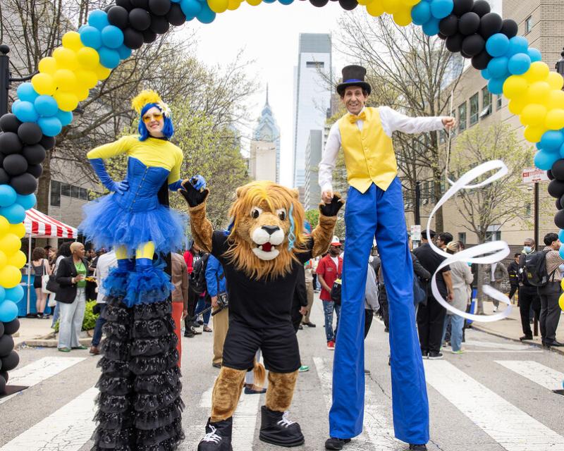 Mascot Roary and stiltwalkers at the block party