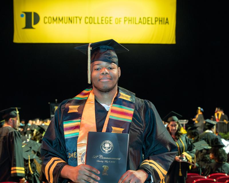 David Emdin Holding his diploma, in a cap and gown
