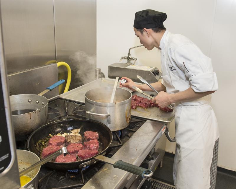 Culinary arts student using a meat thermometer while cooking