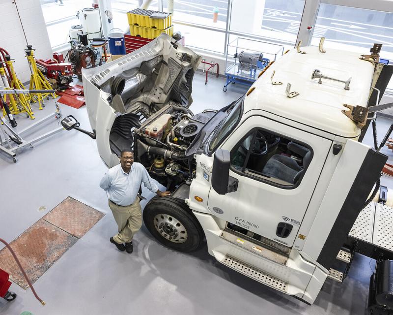 Mechanic standing in front of open truck engine