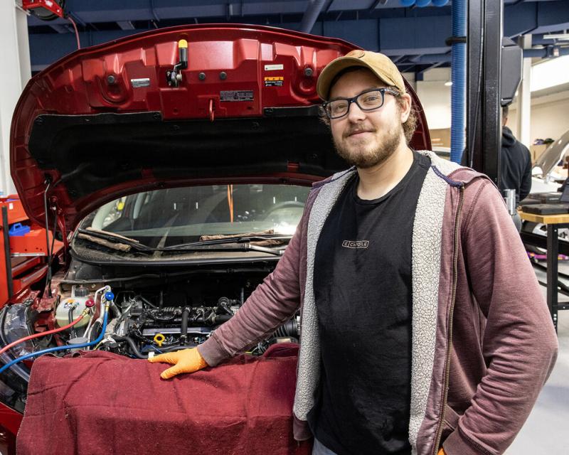 transportation technologies student standing at hood of car